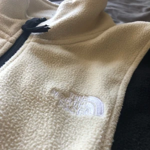 The North Face fleecejacka  - Snygg The North Face fleecejacka i beige och svart färg. Den är tunn i ett skönt material och väger knappt någonting. Nypris ca 1200kr, bra skick. Storlek S men sitter loose. Kontakta mig vid funderingar eller för mått. Pris kan diskuteras.😁