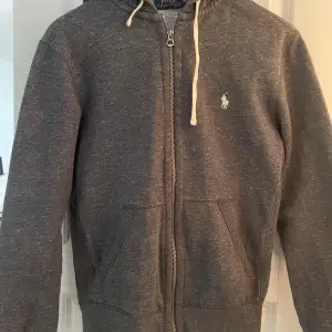 Ralph Laurent Zip hoodie säljes på grund av att den är för liten. Varan är använd men är i bra skick. Varan har fått en skada på ärmen men är lätt att sy ihop(det syns på bild)