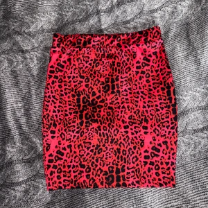 Kjol med leopard mönster svart röd - Aldrig använd, helt ny, se alla bilder för mått och kvaliteten. Unik svart röd mönstrad kjol från Nelly. Storlek S, passar XS med.