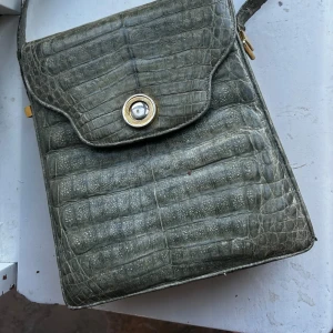 Grön vintage väska - Säljer denna vackra ljusgröna vintage väskan från 50/60-talet med guld detaljer. Handtaget är lite skadat (se bild) men annars är den i väldigt bra skick. Pris går att diskutera! Hör av dig vid intresse💛