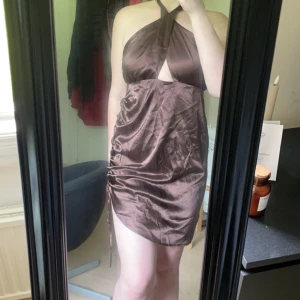 Fest klänning - En fin fest klänning i silkes tyg. Klänningen är öppen i ryggen och man knyter den i nacken. Den har även ett snöre på vänster sida som man kan dra åt beroende på hur man vill ha den.