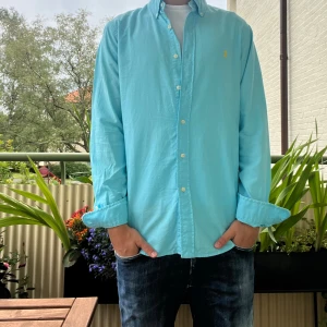 Ralph lauren skjorta - Snygg Ralph lauren skjorta. Ljusblå färg med en gul logga. Säljer eftersom jag inte använder längre. Utmärkt skick