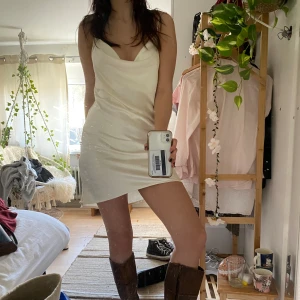 Vacker klänning - Otroligt fin vit/beige glansig klänning. Perfekt till balen eller studenten. Lite sliten i tyget och har några små fläckar som syns om man kollar noga, har inte ansträngt mig för att få bort dem så det kan säkert gå.