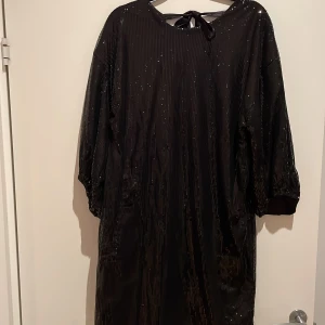 Svart paljettklänning från Kappahl - Normal i storleken lite oversize och aldrig använd. Lite urringad i rygg med knyt och halvlånga puffärmar.