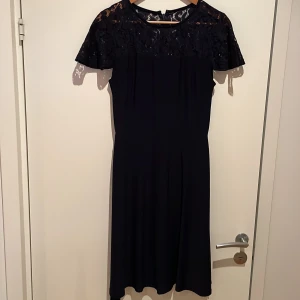 Tidlös och klassisk klänning från Ralph Laurent i marinblå och med spets upptill. - Normal storlek och i nyskick bara använd en gång.