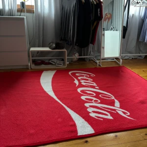 Coca-Cola Matta - Säljer min vintage matta från CocaCola. Finns ej att köpa längre. Storlek 2x3 meter. Skick som bild. Inga hål eller fläckar
