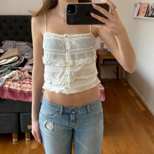 Detaljerat linne - Vitt linne från Mango med många detaljer. Både volanger, broderade kanter, knappar och små pärlor. Väldigt gullig och fin till sommaren. Står storlek S på lappen, passar även xs bra. Man får med en extra knapp också.