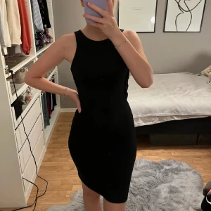 Svart cut-out klänning - Klänning med cut-outs på sidorna. Djup urringning i ryggen i storlek XS från Bikbok. Väldigt fint skick!