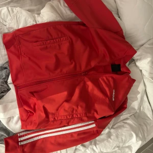 Röd adidas kofta  - Den är i helt okej skick den har några små skador ja kan skicka bättre bilder på om man är intresserad 