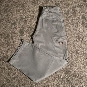 Dickies byxor gråa - Storlek 32/32, gråa dickies double knee arbetsbyxor, väldigt bra skick då byxorna inte använts så mycket, inga defekter alls! 