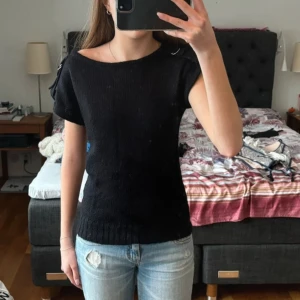 Topp mer detalj  - Svart stickad tröja med metallspännen på axlarna🩶