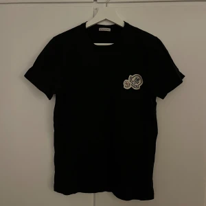 Moncler double logo t-shirt - Säljer nu denna snygga Moncler double logo t-shirt i strorlek 1 vilket motsvarar S men är lite liten i storleken. Den är lite skrynklig vilket knappt syns när man har på den men annars i perfekt skick och är äkta! Skriv gärna vid minsta fundering! 