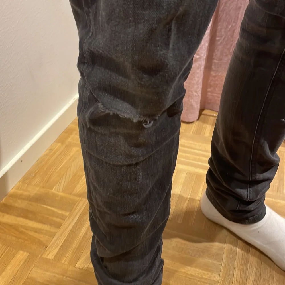 Nudie jeans i en väldigt snygg tvättad svart färg. Skick: 6,5 då de har ett hål på knät men som ändå gör jeansen lite snyggare! Nypris: 1600kr. Killen på bilden är 182cm lång. OBS är öppen för byten! . Jeans & Byxor.