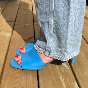 H&M blå mules  - Säljer dessa blå mules från H&M i storlek  i storlek 40. Jag har normalt sett storlek 40/41 och dem passar mig! Bekväma och ganska enkla att gå i samt riktigt snygga till jeans! Det svarta på sulan är från ett plåster och syns ej på💕