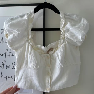 En kort och krämvit topp från H&M i storlek 36🤍 - En superfin och smickrande topp som är i mycket bra skick! Den är i en kortare modell och har otroligt fina detaljer och lite puffiga armar! 😍Passar framförallt dn storlek XS men även S!