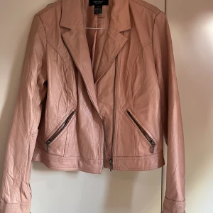 Jacka - Rosa skinnjacka i nyskick från ellos i storlek 42 men passar 38. Står ej om det är äkta skinn men tror inte det tyvärr 