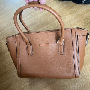 Märkesväska brun - Brun märkesväska från charles&keith. Den är i fint skick. Funkar även som axelremsväska. Rymlig. Guldiga detaljer. 
