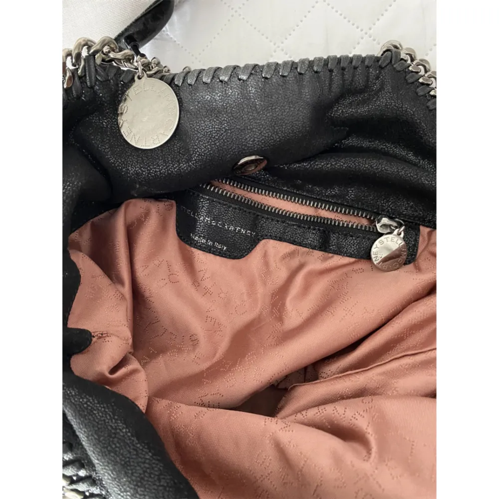 Säljer min Stella McCartney väska som jag köpt från Vestiaire Collective. Den är i modellen Falabella leather tote i storlek medium. Väskan är i veganskt läder och har en liten defekt på baksidan, se bild.. Asusteet.