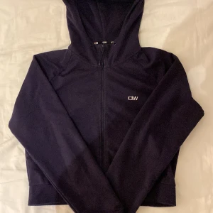 ICIW tränings ziphoodie i en kortare modell - En fin mörkblå träningszip i en lite kortare modell med märke på framsidan. Bara använd ett fårtal gånger.