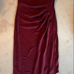 Vinröd asymmetrisk klänning i stretchigt material. Bodycon