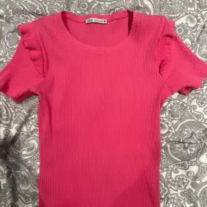 Superfin rosa t-shirt med volanger på axlarna💕Tröjan är väl använd men finns inga defekter. Den passar mig som vanligtvis har S-M i kläder och har väldigt stretchigt material. Skriv för fler bilder💕 Original pris tror jag var 200-250kr.