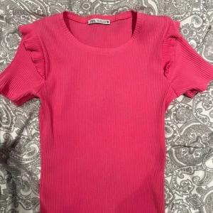 Rosa volang topp - Superfin rosa t-shirt med volanger på axlarna💕Tröjan är väl använd men finns inga defekter. Den passar mig som vanligtvis har S-M i kläder och har väldigt stretchigt material. Skriv för fler bilder💕 Original pris tror jag var 200-250kr.