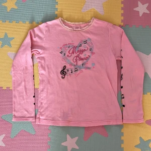 Rosa mezzo piano tröja (140cm) - Säljer för sm att jag jag tröttnat på den och det inte är min stil längre. Använd ett par gånger. Helt fläck fri och är ej sönder. Den har notor på armarna.  Kontakta om du har frågor, köp är på!