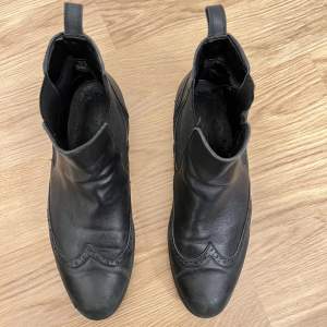 Låga svarta läder boots från Bianco, med mönster. Ordinarie pris 1200kr. Använt skick. Har några repor vid tå parti, men inte märkbart när man smörjer in skorna. Tyg vid hälen utsliten på insidan. Sköna lätta och mjuka skor. Varit mina favorit skor. 