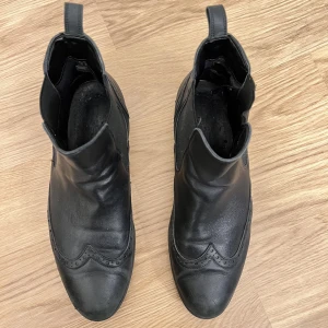 Bianco läder boots - Låga svarta läder boots från Bianco, med mönster. Ordinarie pris 1200kr. Använt skick. Har några repor vid tå parti, men inte märkbart när man smörjer in skorna. Tyg vid hälen utsliten på insidan. Sköna lätta och mjuka skor. Varit mina favorit skor. 