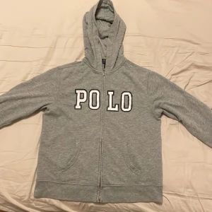 Ralph Lauren zip hoodie - Säljer min gråa Ralph lauren zip hoodie då den nu är för liten för mig. Tröjan är grå och i storleken 14-16. Hoodien har inga defekter och hör gärna av er vid frågor eller intresse.
