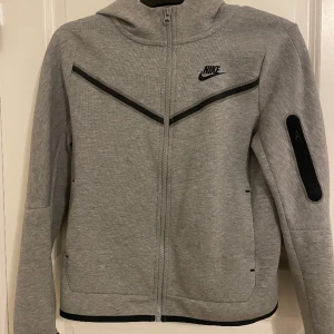 Nike kofta med fick på ärmen  - Mysig Nike kofta med material på bomull. Använd några gånger dock inga tecken på användning. Nypris 1195kr men säljer för 399kr. Storlek 158-172 men passar XS/S