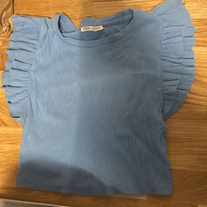 Tröja med volanger - En blå tröja från zara med volanger. Kommer inte till användning och säljer därför. Storlek S men passar även M då den är strechig.