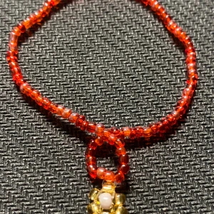 Rött pärlarmband  - Skit gulligt rött armband med en guldig blomma som detalj