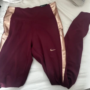Nike tränings tights - Helt nya träningstights från Nike! Vinröda med guld på sidorna! Finns även matchande sport bh jag har lagt upp!!!!! ❤️
