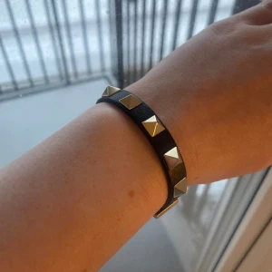 Valentino armband - Säljer mitt svarta armband från Valentino! Säljs tillsammans med tillhörande box, dustbag, 2 extra nitar samt äkthetsbevis 🥰