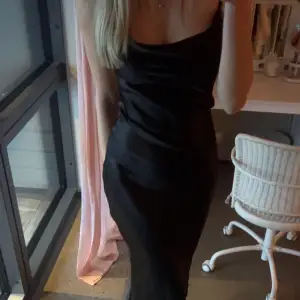 En super fin svart klänning i glansigt material , med fina detaljer i ryggen. Klänningen är aldrig använd. Perfekt till middagen eller kanske mösspåtagningen🖤