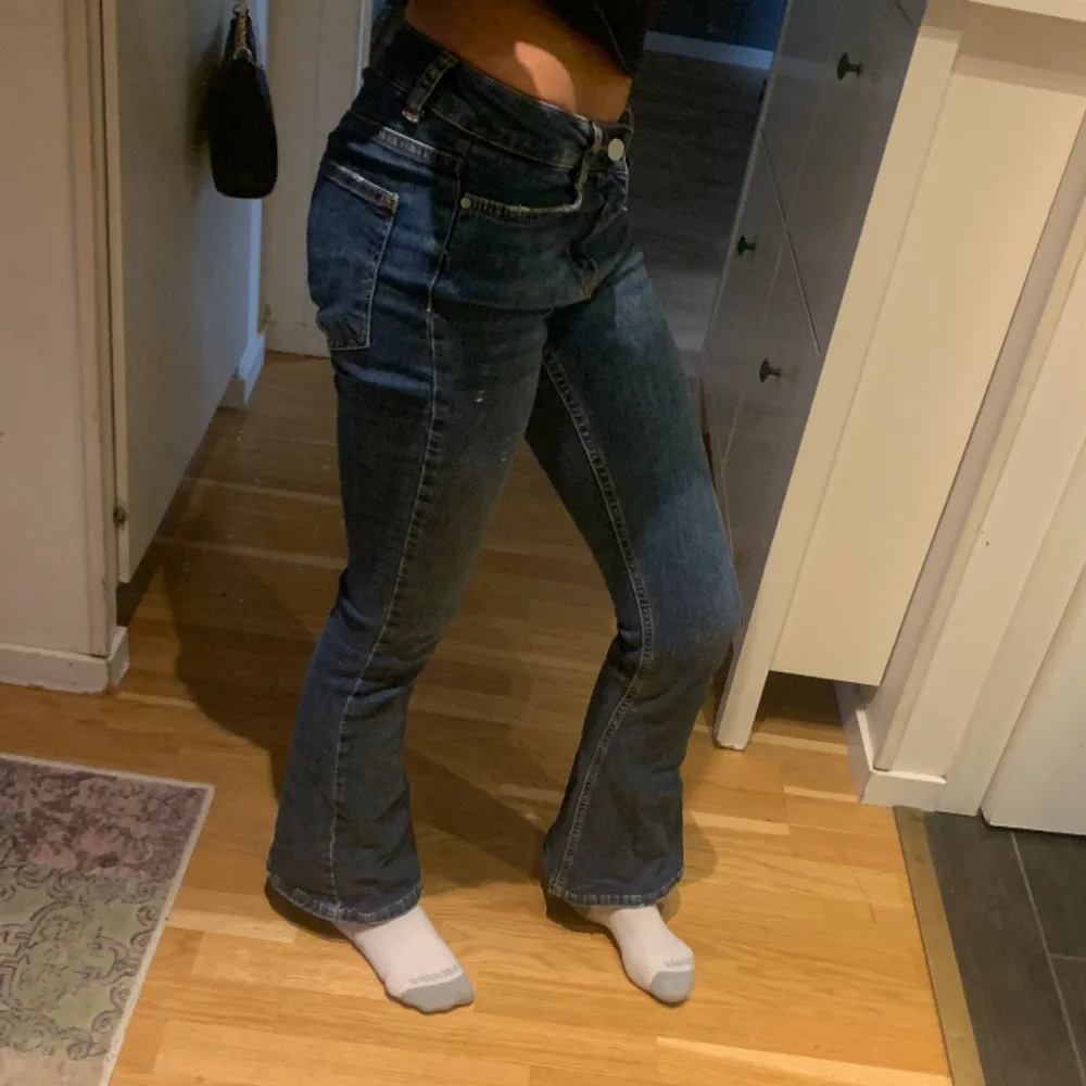 Ett par mörblåa jeans från Gina tricot. Lågmidjade och utsvängda.  Midjemått:32cm Innerbenslängd: 75cm. Jeans & Byxor.