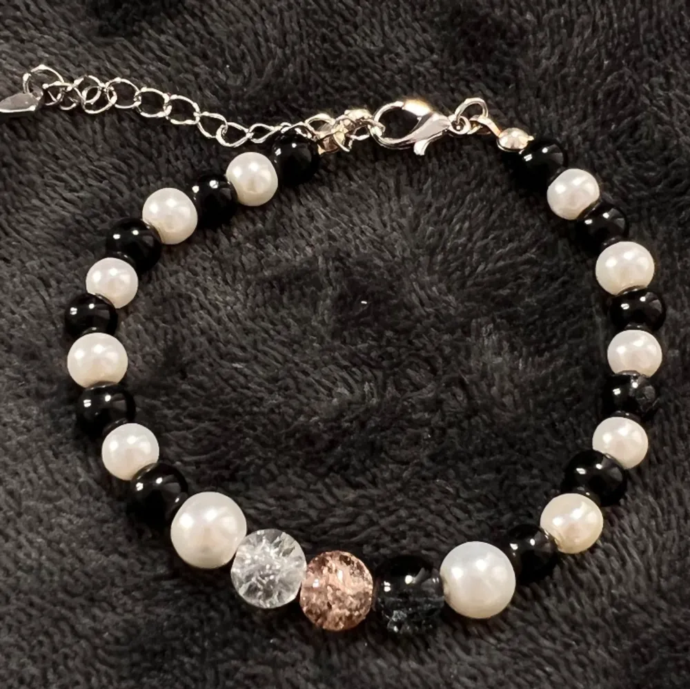 Handgjort pärlarmband med svart-vita pärlor och krackelerade pärlor i mitten och silvrigt spänne. Justerbar passform mellan 19-25 cm.💕. Accessoarer.