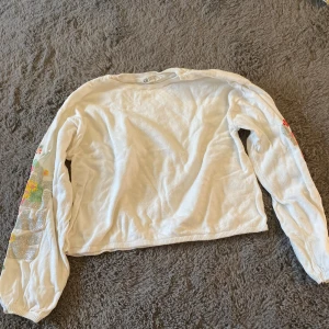 Vit tröja - Vit tröja med blommor på ärmarna. Använd ett fåtal gånger. Säljer pga för liten