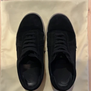 Svarta Axel arigato skor - Jag säljer ett par svarta Axel arigato skor i materialet mocka. Skorna är i helt okej skick, sulan är lite smutsig men annars är skorna i bra skick.