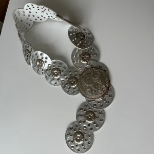 Trendig bälte - Silver belt with sircle plait details. It fits me with a few sircles to spare, and I use size 38/m in pants. The buckle is broken, but you can still use it with a tie or piece of string to secure it.