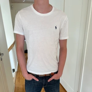 Ralph Lauren t-shirt - Tja! Säljer nu denna klassiska vita Polo Ralph Lauren t-shirten då jag har växt ur den. Skick 8,5/10. Storleken är M men den är ”Custom Slim Fit” vilket gör att den sitter mer som S. Modellen är 185 cm och väger 75. Hör av er vid minsta fundering😃