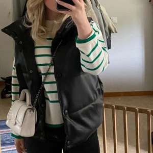 Svart skinnväst från NA-KD  - En jättefin skinnväst i stl 36, köpt på NA-KD. Nypris 739 kr, mitt pris 250 kr. Tyvärr kommer västen inte till så mycket användning längre, därav har jag valt att sälja ☀️ Tveka inte att höra av er för mer bilder och info!🧡  (andra bilden är lånad) 