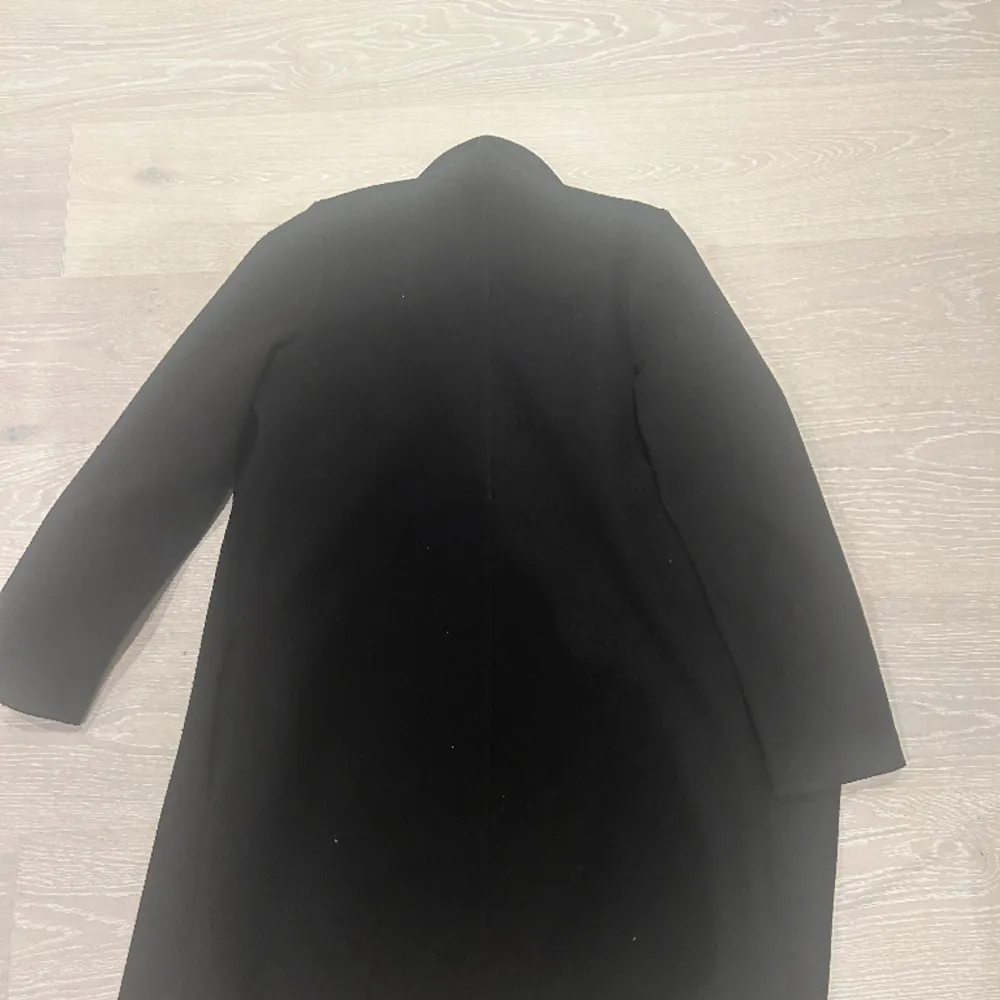 En svart kappa i storlek s, ordinarie pris 700 säljer för 500. Jackor.