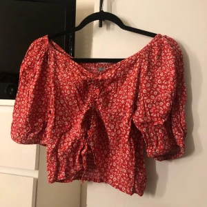 Blus/topp - En super söt rödblommig blus/topp från Lindex. Använd fåtal gånger. Den har resor i mitten och kan knytas till magtröja ❤️