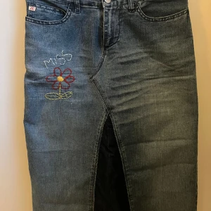 Unik jeanskjol - Unik midi jeanskjol med brodering på ena sidan. Köpt second hand men är från miss sixty🩷. Säljer så den tyvärr är för liten för mig. Skriv om ni har några andra frågor!