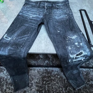 DSQ2 Jeans svarta Ripped - Tja säljer mina DSQ2 jeans för dom används ej längre tyvärr.  prod nummer: s74LB1362  Storlek 48 Endast tvättade 1 gång enligt Dsq2 riktlinjer Finns kvitto, påse, DSQ2 egna jeans hängare och extraknappar 