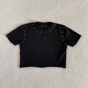 ASOS Design croppad t-shirt med nitar - Supersnygg t-shirt i lite tjockare material från ASOS Design. Använd endast i några timmar, utan anmärkningar. Storlek 34.