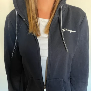 Marinblå champion kofta - En fin och mysig kofta från champion. Den är använd ett fåtal gånger men har blivit sliten i tvätten. Storleken är M men passar på S.