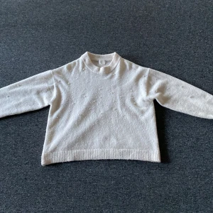 Vit stikad tröja - En stikad tröja med pärlor på. Lite längre en vad den är på bilden.